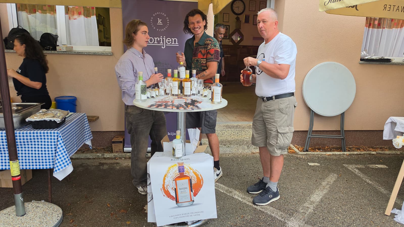 Štand destilerije Korijen iz Kuline s bocama rakija i posjetiteljem koji kuša uzorak