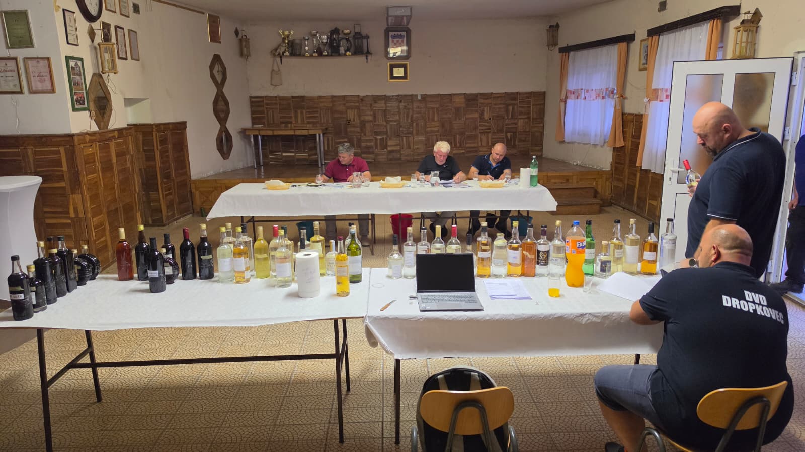 Dvorana Vatrogasnog doma DVD-a Dropkovec tijekom ocjenjivanja — stolovi s uzorcima u prvom planu, stručno povjerenstvo u pozadini