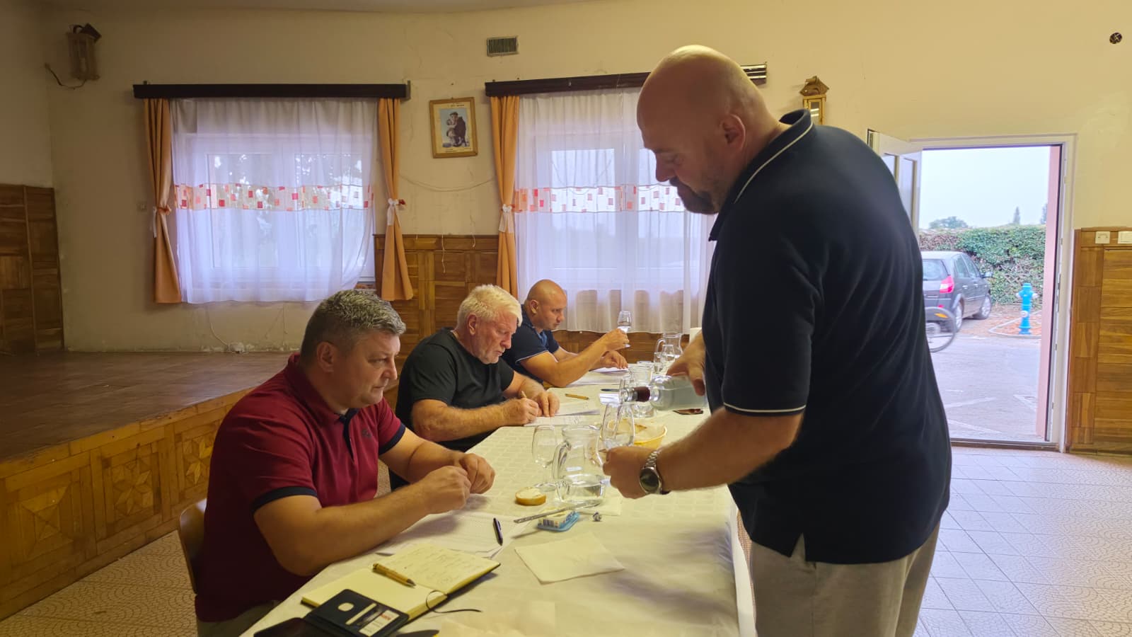 Posluživanje uzorka rakije stručnom povjerenstvu koje upisuje ocjene za stolom