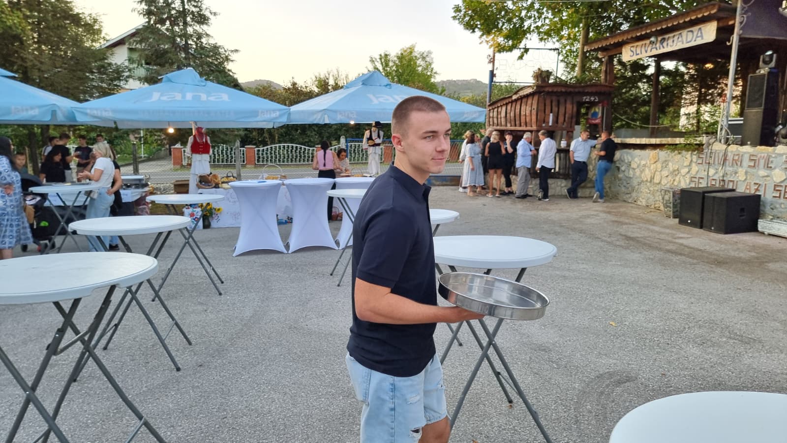 Dvorište vatrogasnog doma u Dropkovcu u predvečerje Slivarijade — stolovi, suncobrani i pozornica