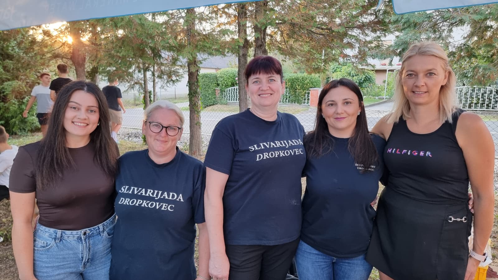 Nasmijane domaćice u majicama Slivarijada Dropkovec ispred štanda s jelima